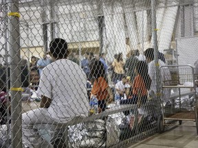 In this photo provided by U.S. Customs and Border Protection, people who've been taken into custody related to cases of illegal entry into the United States, sit in one of the cages at a facility in McAllen, Texas, Sunday, June 17, 2018.