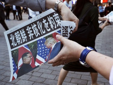 A staff of Japanese newspaper Mainichi Shimbun distributes their extra edition which report the summit between U.S. President Donald Trump and North Korean leader Kim Jong Un in Singapore, near Shimbashi Station in Tokyo, Tuesday, June 12, 2018.  The headline reads, "North Korea promises to denuclearize". (Suo Takekuma/Kyodo News via AP) ORG XMIT: TKSK809
