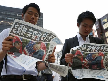 People look at the extra edition of  Japanese newspaper Mainichi Shimbun reporting the summit between U.S. President Donald Trump and North Korean leader Kim Jong Un in Singapore, at Shimbashi Station in Tokyo, Tuesday, June 12, 2018.  The headline reads: North Korea promises to denuclearize. (Suo Takekuma/Kyodo News via AP) ORG XMIT: TKSK808