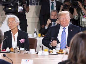 U.S. President Donald Trump, right, takes his seat after arriving late for the G7 and Gender Equality Advisory Council Breakfast, as IMF Managing Director Christine Lagarde looks on, left, at the G7 leaders summit in La Malbaie, Que., on Saturday, June 9, 2018.