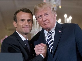 FILE - In this Tuesday, April 24, 2018 file picture President Donald Trump and French President Emmanuel Macron embrace at the conclusion of a news conference in the East Room of the White House in Washington. Tensions are mounting between French President Emmanuel Macron and U.S. President Donald Trump, meeting Friday with other leaders at the G-7 summit in Canada. Just six weeks ago Macron and Trump exhibited their friendship at a state dinner in Washington but today Macron is positioning himself to lead the anti-Trump brigade at the G7.