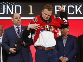 Brady Tkachuk puts on a Senators jersey after being selected by the team during the NHL draft in Dallas on Friday night.