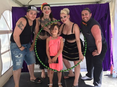 Members of Capital Tease pose with a young fan after a performance at the Glowfair Festival.