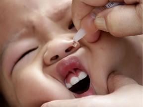 File: A health worker administers a vaccine to a baby.