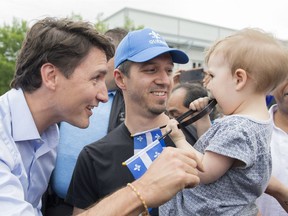 Prime Minister Justin Trudeau, left, greets a man and young girl during a visit to a Saint-Jean Baptiste day celebration in Montreal, Saturday, June 23, 2018.