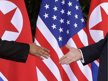 U.S. President Donald Trump, right, reaches to shakes hands with North Korea leader Kim Jong Un at the Capella resort on Sentosa Island Tuesday, June 12, 2018 in Singapore.