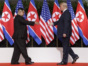 U. S. President Donald Trump and North Korea leader Kim Jong Un reach to shake hands at the Capella resort on Sentosa Island Tuesday, June 12, 2018 in Singapore.