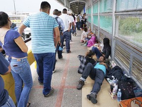 In this Thursday, June 23, 2018 photo, migrant families rest from their travels to Matamoros, Mexico, along Gateway International Bridge which connects to Brownsville, Texas, as they seek asylum in the United States.