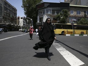 A woman crosses Jomhouri-e-Eslami (Islamic Republic) St. in downtown Tehran, Iran, Saturday, June 9, 2018. For Iran, the so-called "Axis of Evil" has become a lonely party of one as President Donald Trump prepares for direct talks with North Korea. With Saddam Hussein overthrown and Kim Jong Un now preparing for planned meeting in Singapore with Trump, Iran remains the last renegade among former President George W. Bush's grouping of nations opposed to the U.S. It also comes after Trump pulled out of the nuclear deal, worsening Iran's already-anemic economy.