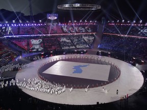 FILE - In this Feb. 9, 2018, file photo, athletes from North and South Korea wave Korean unification flags as they walk on stage during the opening ceremony of the 2018 Winter Olympics in Pyeongchang, South Korea. Hundreds of North Koreans go to the Pyeongchang Games in February, including leader Kim Jong Un's sister Kim Yo-Jong, who conveys her brother's desire for an inter-Korean summit with South Korean President Moon Jae-in.