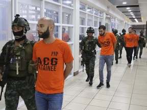 In this photo provided by the Philippine National Police, SAF (Special Action Force) members escort Israeli nationals following a raid at Clark Freeport Zone, Pampanga province, Thursday, June 7, 2018, in Quezon city, northeast of Manila, Philippines. Police say they have arrested nearly 500 people, including eight Israeli nationals, who they say are involved in an online financial fraud that victimized people overseas, including in Australia and South Africa. (Philippine National Police via AP)
