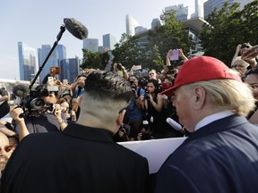 In this June 8, 2018, photo, Kim Jong Un and Donald Trump impersonators, are swamped by members of the media and curious onlookers as they visited the Merlion Park, a popular tourist destination in Singapore. The small island nation of Singapore, which prides itself on law and order, is feeling the pressure of more than 3,000 members of the press arriving for a historic summit between President Donald Trump and North Korean leader Kim Jong Un. Apart from journalists, authorities also have to contend with Kim and Trump impersonators.