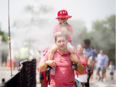 Hector Murillo and his son, Alejandro, 2, enjoy the cool mist after the security screening on the way to Parliament Hill.   Ashley Fraser/Postmedia