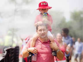 Hector Murillo and his son two-year-old, Alejandro, take advantage of one of the misting stations at Parliament Hill on Sunday.   Ashley Fraser/Postmedia