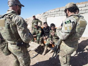 Canadian special forces soldiers, left and right, speak with Peshmerga fighters at an observation post, Monday, February 20, 2017 in northern Iraq.