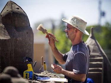 André Poulin works on his sand sculpture Saturday.