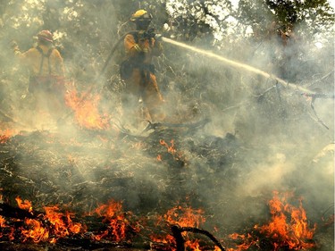 REDDING, CA - JULY 28:  A Cal Fire firefighter mops up hot spots after the Carr Fire moved through the area on July 28, 2018 in Redding, California. A Redding firefighter and bulldozer operator were killed battling the fast moving Carr Fire that has burned over 80,000 acres and destroyed hundreds of homes. The fire is 5 percent contained.