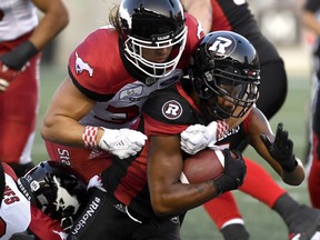 Ottawa Redblacks' Loucheiz Purifoy is tackled by Calgary Stampeders Ante Milanovic-Litre during Thursday's game. (THE CANADIAN PRESS)