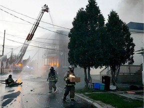 Cornwall firefighter carries a box of kittens retrieved from a house on Alice Street adjacent to the apartment building destroyed by fire on Thursday, July 26, 2018.