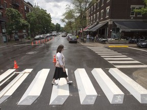 A pedestrian walks a crosswalk painted in a 3-dimensional style for a pilot project, in the Montreal borough of Outremont on Tuesday, July 10, 2018.