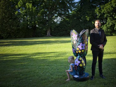 Trevor Sylvain, the artist who painted this tulip, posed for a photo as three-year-old Emilie Hagluand sat on the bottom of the tulip.