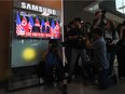 Photographers take pictures next to a television news screen showing the summit between US President Donald Trump and North Korean leader Kim Jong Un in Singapore on June 12.  Watch how TV news covers things, one reader suggests.