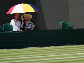 Spectators shelter from the sun beneath umbrellas on the fifth day of the 2018 Wimbledon Championships at The All England Lawn Tennis Club in Wimbledon.
