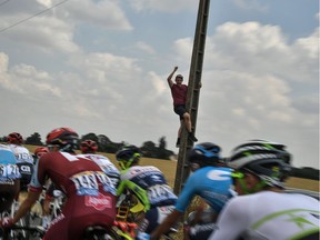 A spectator holding on to a post cheers as the pack rides during the eighth stage of the 105th edition of the Tour de France between Dreux and Amiens on Saturday.