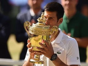 Serbia's Novak Djokovic kisses the winners the trophy after beating South Africa's Kevin Anderson 6-2, 6-2, 7-6 in their men's singles final match on the thirteenth day of the 2018 Wimbledon Championships