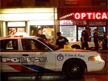 TOPSHOT - Toronto Police officers walk the scene at Danforth St. at the scene of a shooting in Toronto, Ontario, Canada on July 23, 2018. A gunman opened fire in central Toronto on Sunday night, injuring 13 people including a child. Two dead incluiding gunman, police reported.