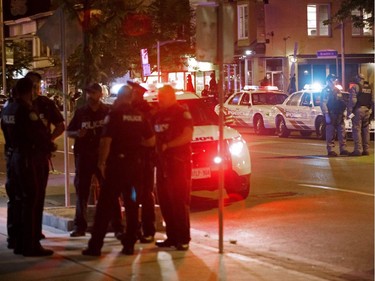 TOPSHOT - Toronto Police officers walk the scene at Danforth St. at the scene of a shooting in Toronto, Ontario, Canada on July 23, 2018. A gunman opened fire in central Toronto on Sunday night, injuring 13 people including a child. Two dead incluiding gunman, police reported.