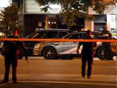 Toronto Police officers walk the scene at Danforth St. at the scene of a shooting in Toronto, Ontario, Canada on July 23, 2018. A gunman opened fire in central Toronto on Sunday night, injuring 13 people including a child. Two dead incluiding gunman, police reported.