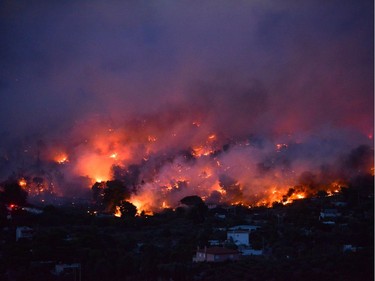 Flames rise as a wildfire burns in the town of Rafina, near Athens, July 23, 2018.