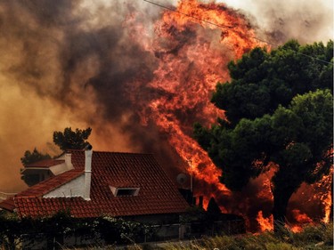 TOPSHOT - A house is threatened by a huge blaze during a wildfire in Kineta, near Athens, on July 23, 2018. More than 300 firefighters, five aircraft and two helicopters have been mobilised to tackle the "extremely difficult" situation due to strong gusts of wind, Athens fire chief Achille Tzouvaras said.