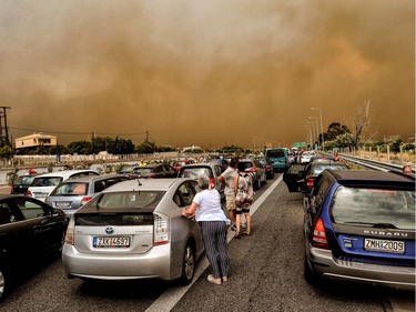 TOPSHOT - Cars are blocked at the closed National Road during a wildfire in Kineta, near Athens, on July 23, 2018. More than 300 firefighters, five aircraft and two helicopters have been mobilised to tackle the "extremely difficult" situation due to strong gusts of wind, Athens fire chief Achille Tzouvaras said.