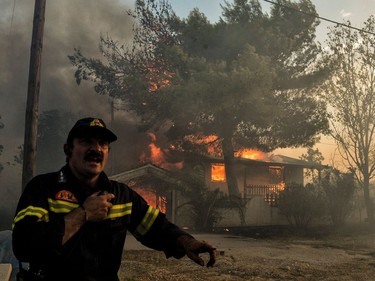 A firefighter reacts as a house burns during a wildfire in Kineta, near Athens, on July 23, 2018. More than 300 firefighters, five aircraft and two helicopters have been mobilised to tackle the "extremely difficult" situation due to strong gusts of wind, Athens fire chief Achille Tzouvaras said.
