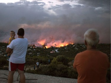TOPSHOT - EDITORS NOTE: Graphic content / People watch a wildfire in the town of Rafina, near Athens, on July 23, 2018.  At least 20 people have died and more have been injured as wild fires tore through woodland and villages around Athens on Monday, while blazes caused widespread damage in Sweden and other northern European nations. More than 300 firefighters, five aircraft and two helicopters have been mobilised to tackle the "extremely difficult" situation due to strong gusts of wind, Athens fire chief Achille Tzouvaras said.