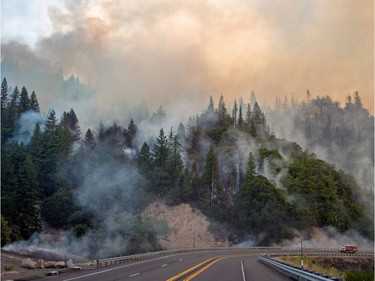TOPSHOT - A fire truck drives along Highway 299 as they Carr fire continues to burn near Whiskeytown, California on July 28, 2018.  The US federal government approved aid on July 28 for California as thousands of firefighters battled to contain a series of deadly raging wildfires that have killed six people, including two young children and their great grandmother, and destroyed hundreds of buildings.