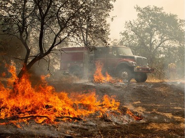 TOPSHOT - Firefighters douse a hotspot near various homes as the Carr fire continues to burn near Redding, California, on July 28, 2018. The US federal government approved aid on July 28 for California as thousands of firefighters battled to contain a series of deadly raging wildfires that have killed six people, including two young children and their great grandmother, and destroyed hundreds of buildings.