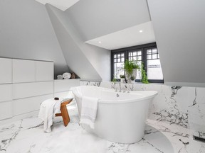 The freestanding oval shaped bathtub is a focal point of the renovation, drawing natural light from the original three-pane dormer window behind it.