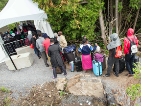 Asylum seekers wait to illegally cross the Canada-U.S. border near Champlain, New York on Aug. 6, 2017.