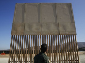 A U.S. Border Patrol agent looks at a border wall prototype Thursday, June 28, 2018, in San Diego. Most Americans seem to favour a wall or security divider of some sort.
