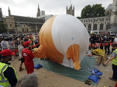 A six-meter high cartoon baby blimp of U.S. President Donald Trump is inflated as a protest against his visit, in Parliament Square backdropped by the scaffolded Houses of Parliament and Big Ben in London, England, Friday, July 13, 2018. Trump is making his first trip to Britain as president after a tense summit with NATO leaders in Brussels and on the heels of ruptures in British Prime Minister Theresa May's government because of the crisis over Britain's exit from the European Union.