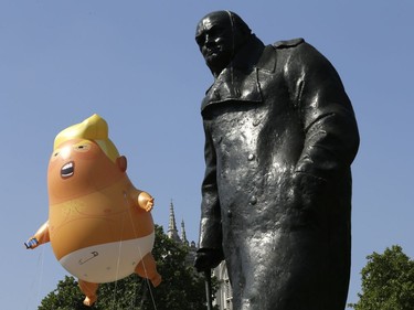 A six-meter high cartoon baby blimp of U.S. President Donald Trump hovers next to the statue of former British Prime Minister Winston Churchill, as it is flown as a protest against his visit, in Parliament Square in London, England, Friday, July 13, 2018.