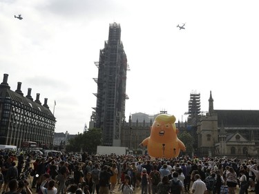 Osprey helicopters fly overhead as a six-meter high cartoon baby blimp of U.S. President Donald Trump is inflated as a protest against his visit, in Parliament Square backdropped by the scaffolded Houses of Parliament and Big Ben in London, England, Friday, July 13, 2018. Trump is making his first trip to Britain as president after a tense summit with NATO leaders in Brussels and on the heels of ruptures in British Prime Minister Theresa May's government because of the crisis over Britain's exit from the European Union.