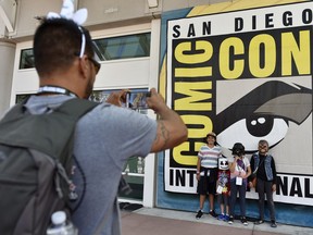 Luis Ramos, left, of San Diego takes a picture of his son Alek, 6, third from right, and daughter Anabel, 11, second from right, and their friends Emiliano Beltran, 12, fourth from right, and Isabel Beltran, 10, before Preview Night at the 2018 Comic-Con International at the San Diego Convention Center, Wednesday, July 18, 2018, in San Diego.