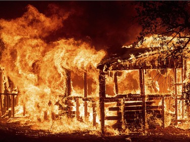 FILE - In this Thursday, July 26, 2018 file photo, a structure burns as the Carr fire races along Highway 299 near Redding, Calif.  In the last year, fires have devastated neighborhoods in the Northern California wine country city of Santa Rosa, the Southern California beach city of Ventura and, now, the inland city of Redding. Hotter weather from changing climates is drying out vegetation, creating more intense fires that spread quickly from rural areas to city subdivisions, climate and fire experts say. But they also blame cities for expanding into previously undeveloped areas susceptible to fire. AP Photo/Noah Berger, File) ORG XMIT: LA608