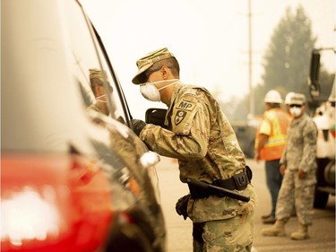 An Army National Guard specialist speaks to a driver at a checkpoint as the Carr Fire burns in Redding, Calif., on Saturday, July 28, 2018. Thousands of residents remain evacuated as the deadly blaze threatens homes in Redding and surrounding communities.