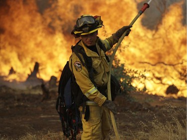 A firefighter makes a stand in front of an advancing wildfire as it approaches a residence Saturday, July 28, 2018, in Redding ,Calif.