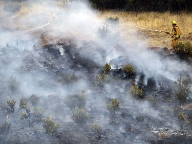 Firefighters hose down hot spots from a wildfire Saturday, July 28, 2018, in Redding, Calif.